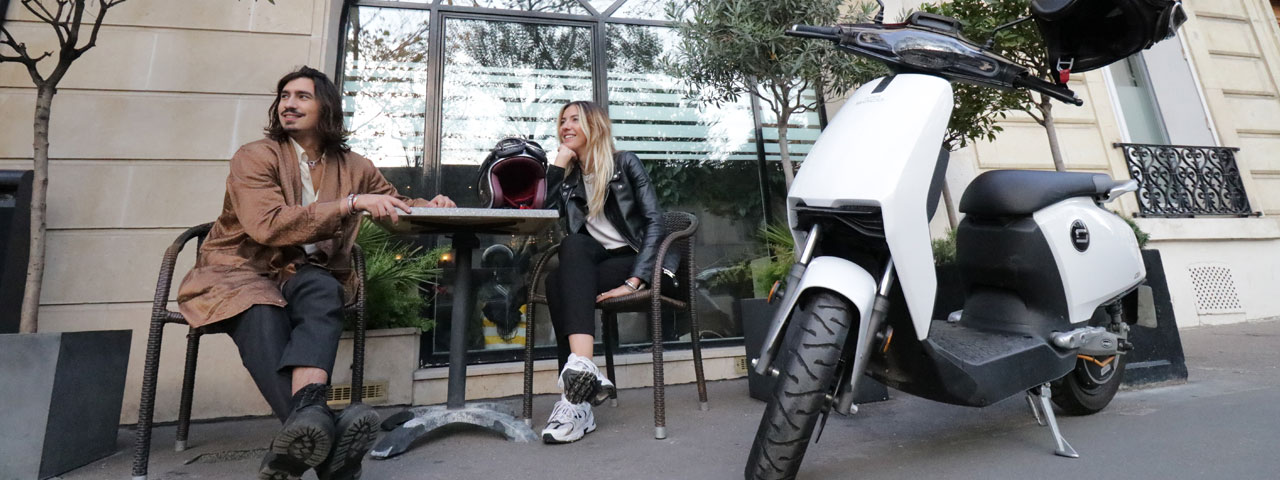 Couple de parisien à la terrasse d'un café à côté d'un Super Soco CU-X