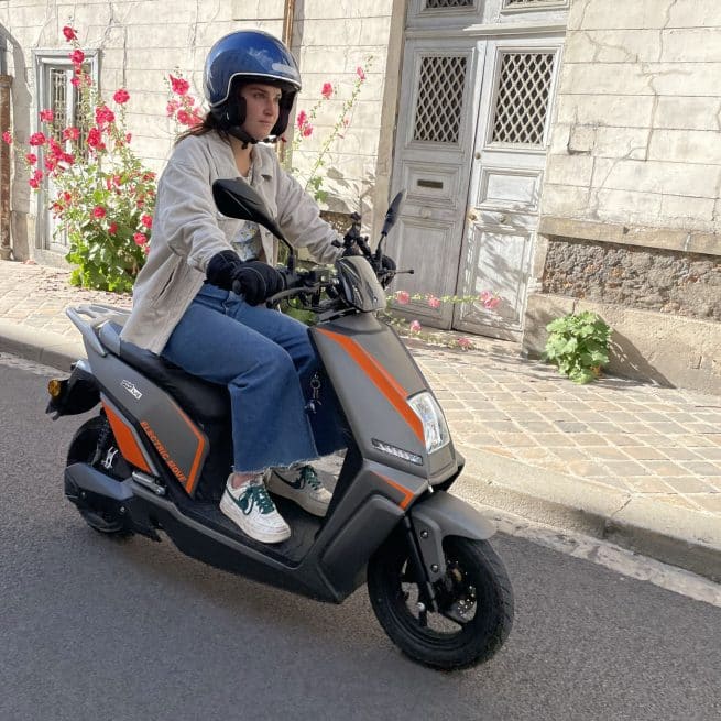 Jeune fille circulant sur son Pink Me gris avec sticker orange