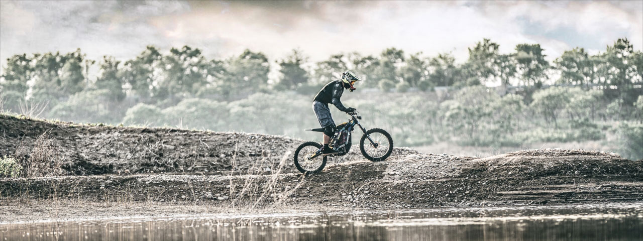 La Sur-Ron Light Bee Off Road et son pilote sur les berges d'un lac