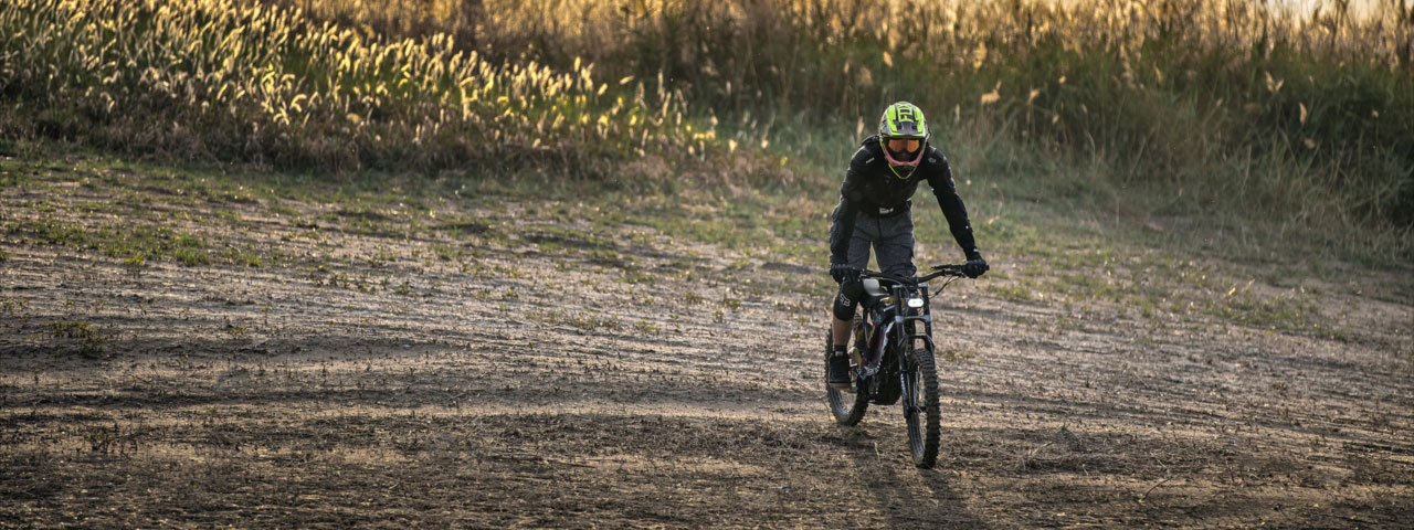 La Sur-Ron Light Bee Off Road et son pilote près d'un plan d'eau