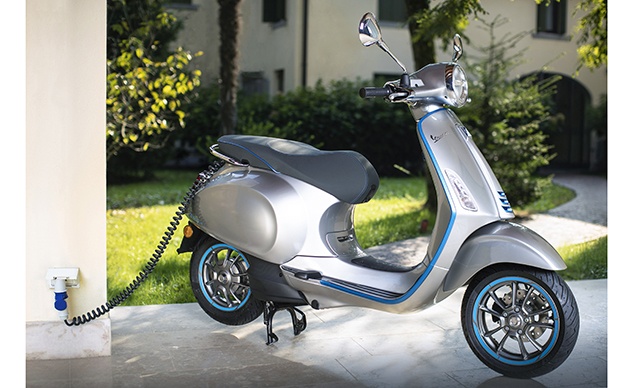 Vespa Elettrica bleue et grise en train de se recharger.