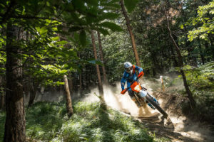 La KTM Freeride XC E et son pilote, sur un chemin à travers une forêt