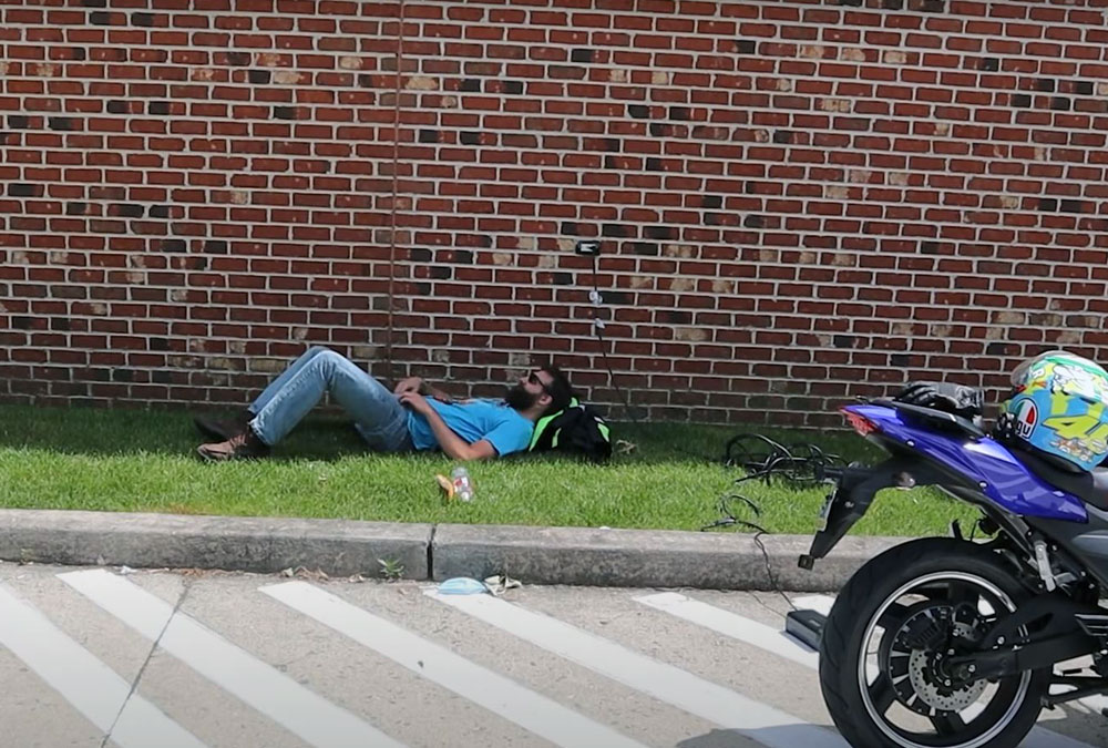 Bikes and Beards allongé au côté d'une moto électrique chinoise en train de charger