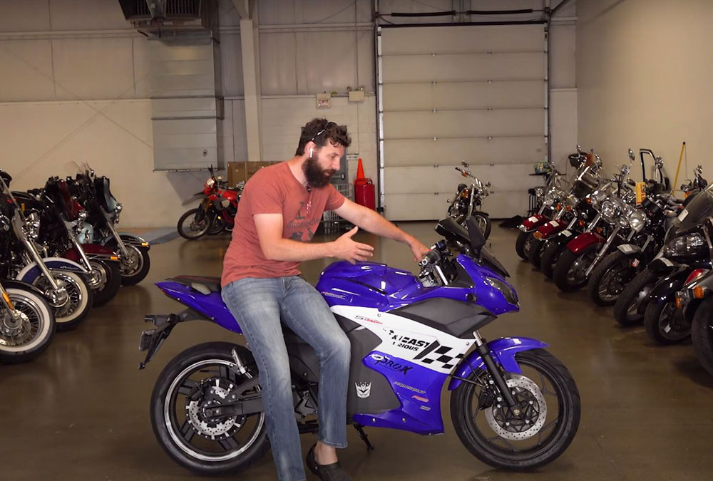 Bikes and Beards dans son garage avec une moto électrique chinoise