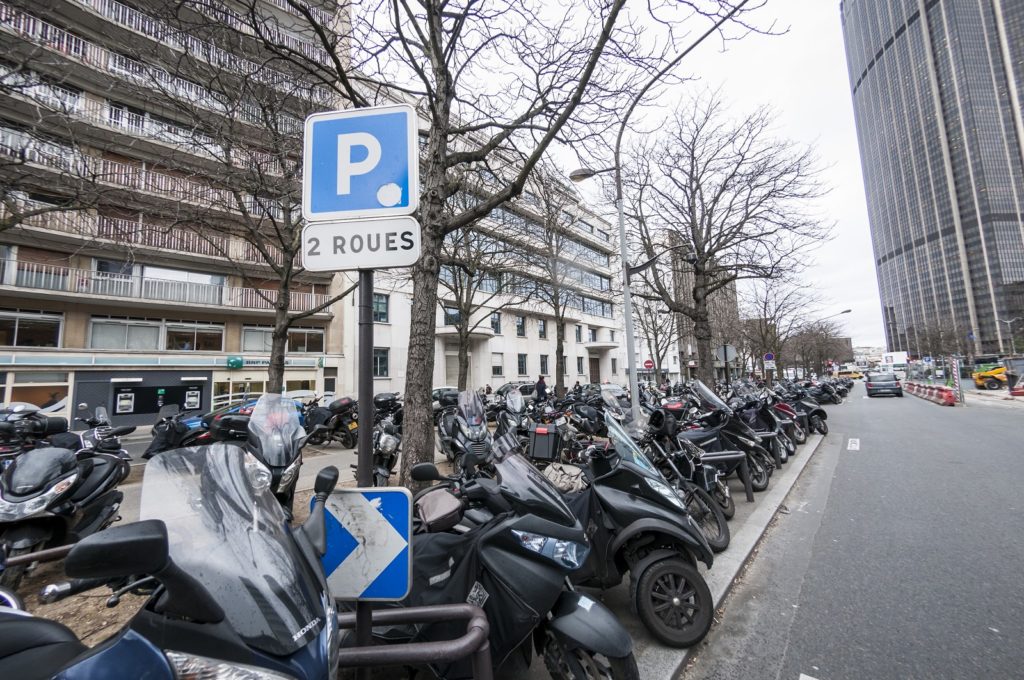 Une rue parisienne dont le parking est empli de 2 roues