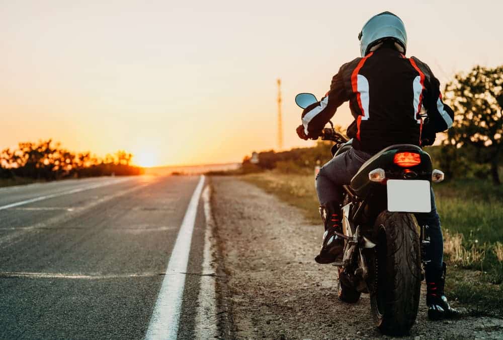 Motard au bord de la route au soleil couchant