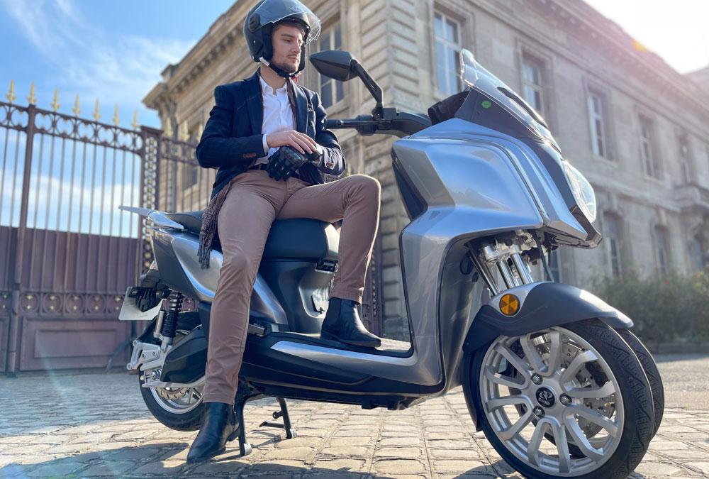 Le scooter 3 roues électrique Rider 3RS+ avec son conducteur garé sur un trottoir