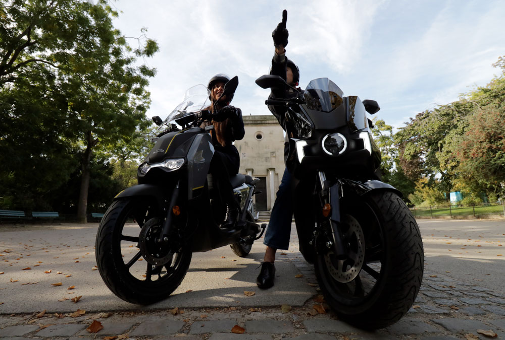 Les scooters électriques Silence S01 et Super Soco CPX avec leurs conducteurs dans un square