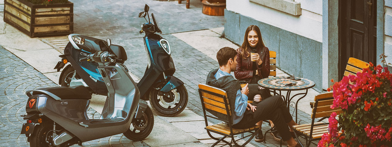 Couple à la terrasse d'un café, leurs deux Yadea C Umi garés à côté