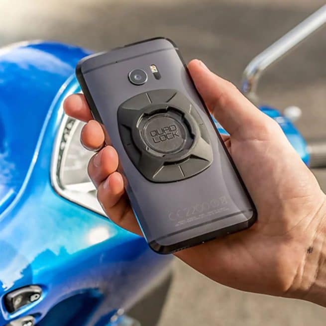 Adaptateur universel QuadLock collé sur un téléphone devant un scooter bleu