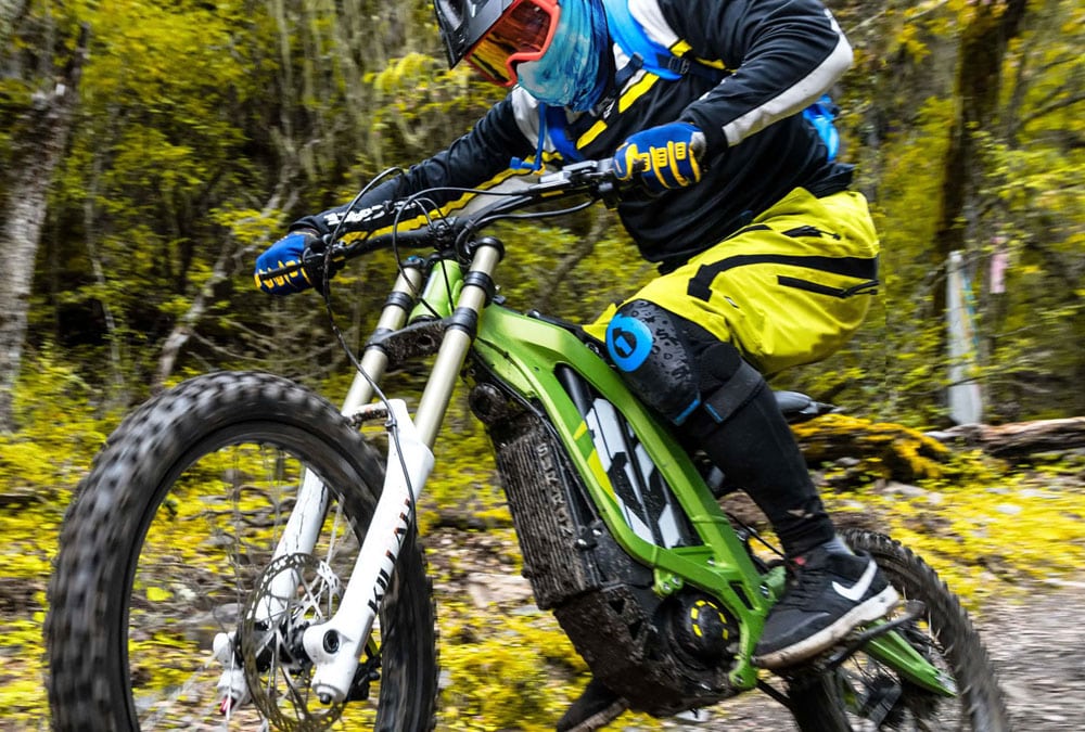 Pilote d'une motocross électrique en train d'effectuer un saut durant une descente