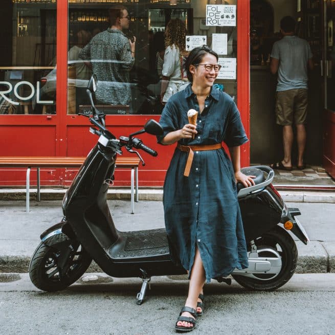 Jeune femme assise sur un yadea G5 Pro tout en mangeant une glace