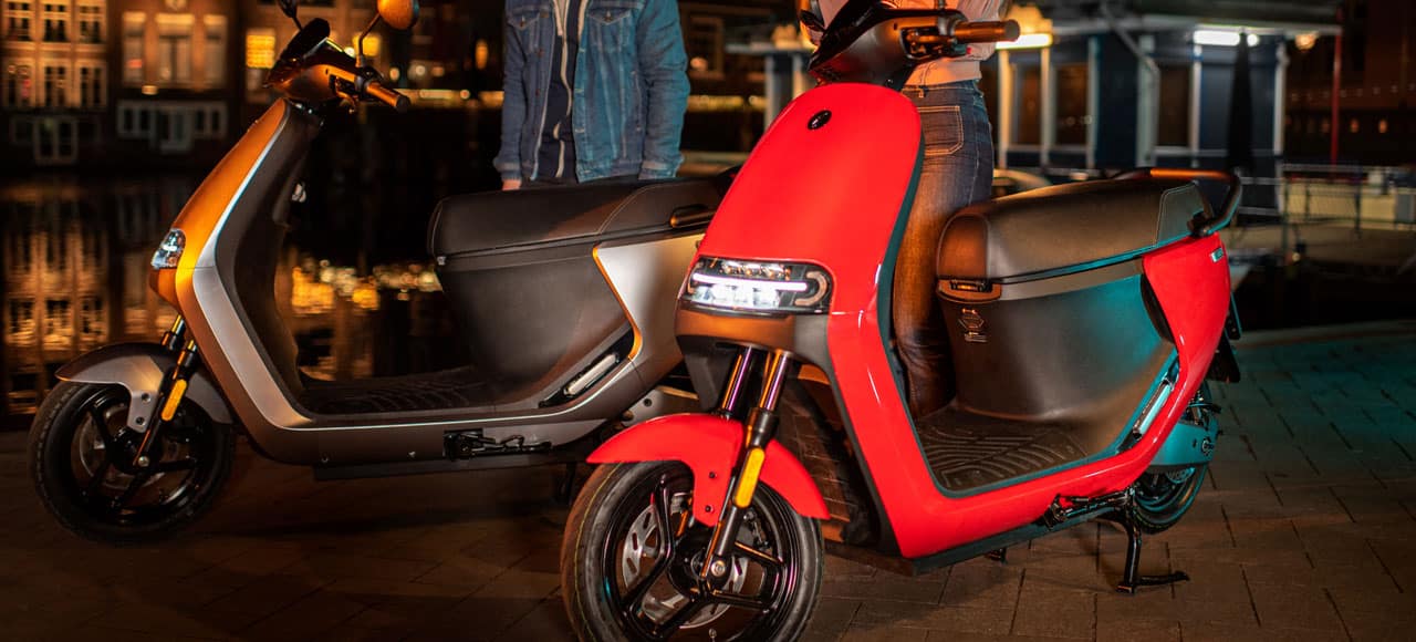 Deux Segway E110S, un rouge et un gris garé dans une ville, la nuit.