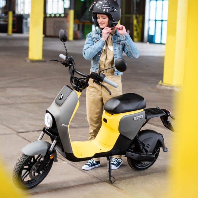 Jeune femme en train d'attacher son casque près d'un Segway B110s jaune