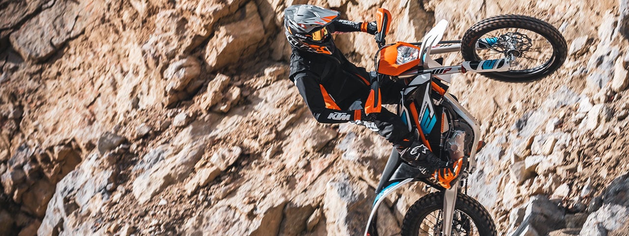 Une KTM freeride E-XC et son pilote sur un terrain très rocailleux