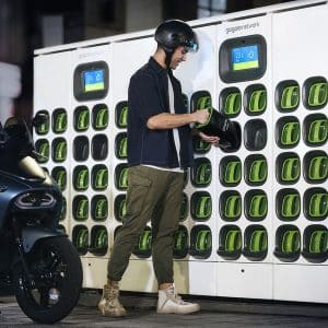 Un utilisateur échange une batterie Gogoro dans une station de swapping Sweetch, aux côtés de son scooter électrique